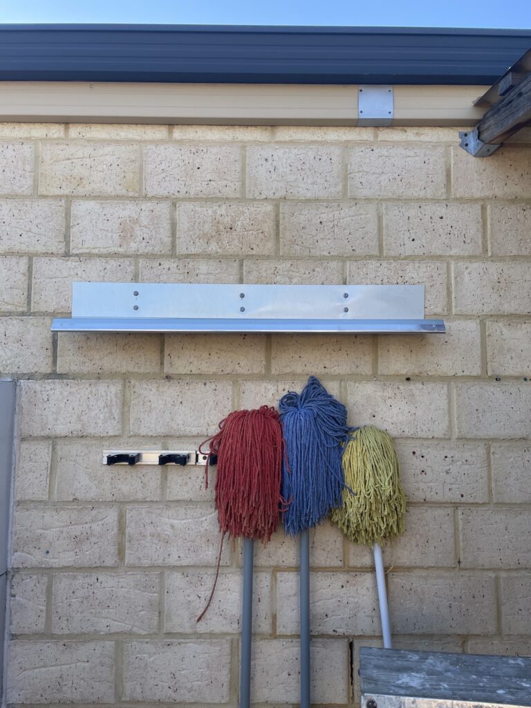 Canopy-style flashing shelf protecting stored mops from bird droppings