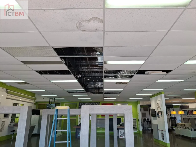 Stained ceiling tile and open ceiling grid before tile and T-bar replacement