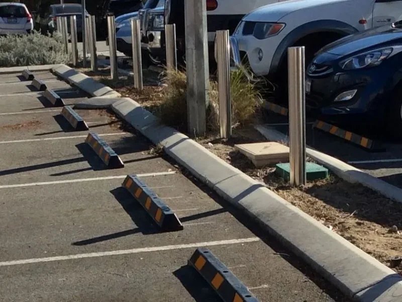 Wheel stops and stainless steel bollards along a car park garden edge