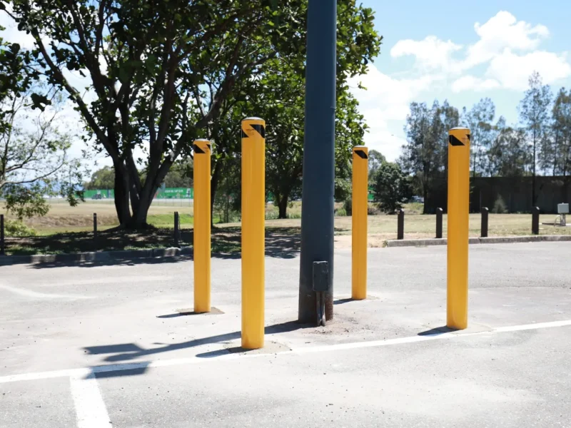 Yellow bollards protecting a light pole in a commercial car park