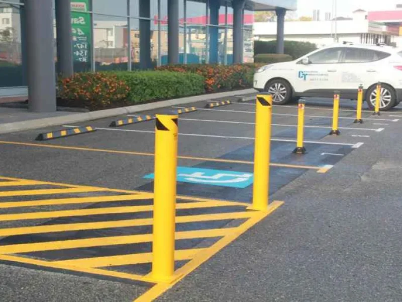 Yellow bollards, wheel stops and accessible bay line marking at a shopping centre car park