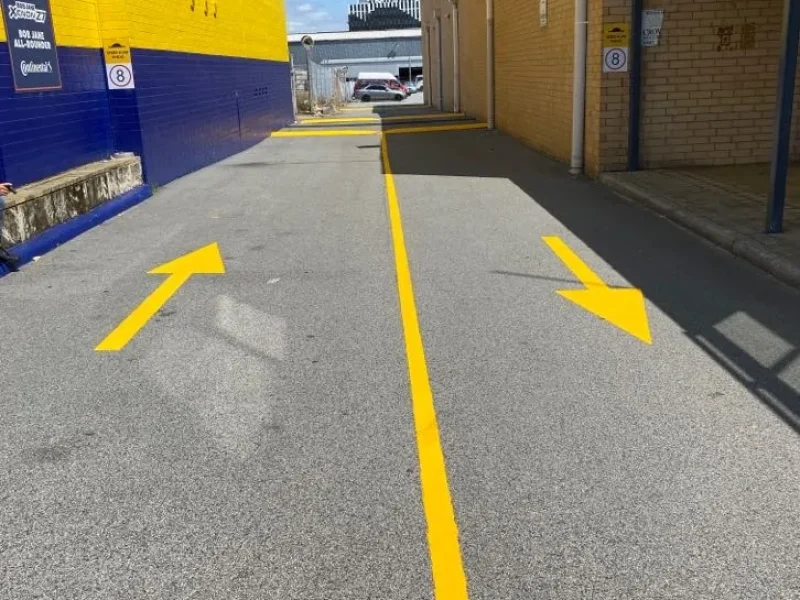 Yellow directional arrows and centre line marked in a Perth commercial laneway