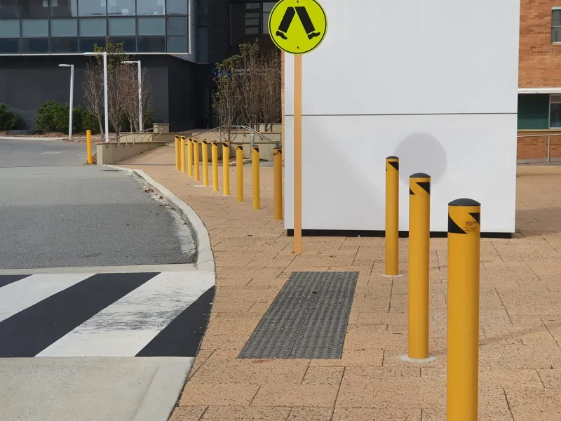 Yellow bollards protecting a footpath and kerb at a commercial building